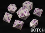 White base color dice with purple graphics and numbers. There are also squiggles, little flowers and cute little floof dudes on the dice. They are adorable. 